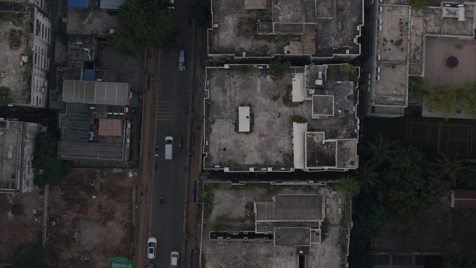 Top-down drone photo of a Dhaka street with polygons around each rooftop, tree, car, van and motorbike, and the road as one region